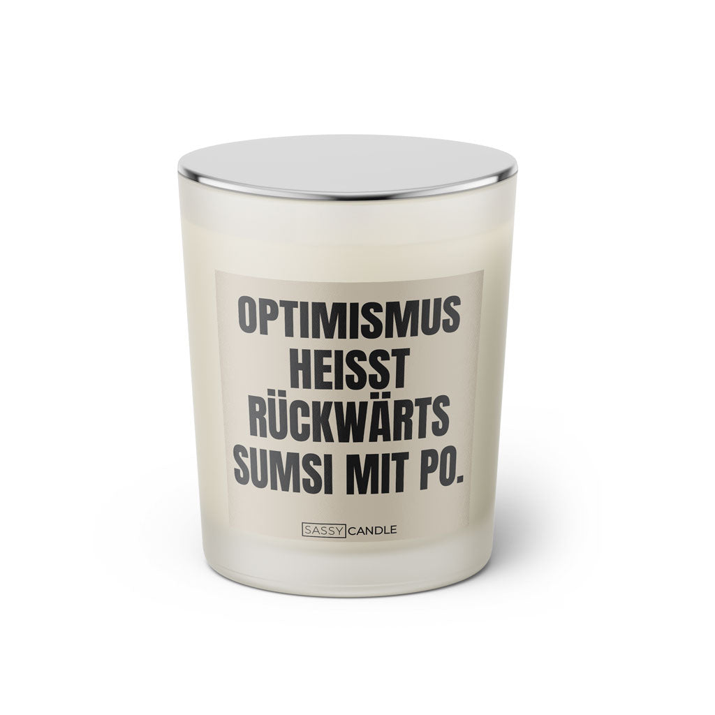 Duftkerze mit witzigem Spruch: Optimismus heißt rückwärts Sumsi mit Po. Farbe beige und schwarze Schrift. Kerzenglas mit silbernem geschlossenem Deckel von SassyCandle.