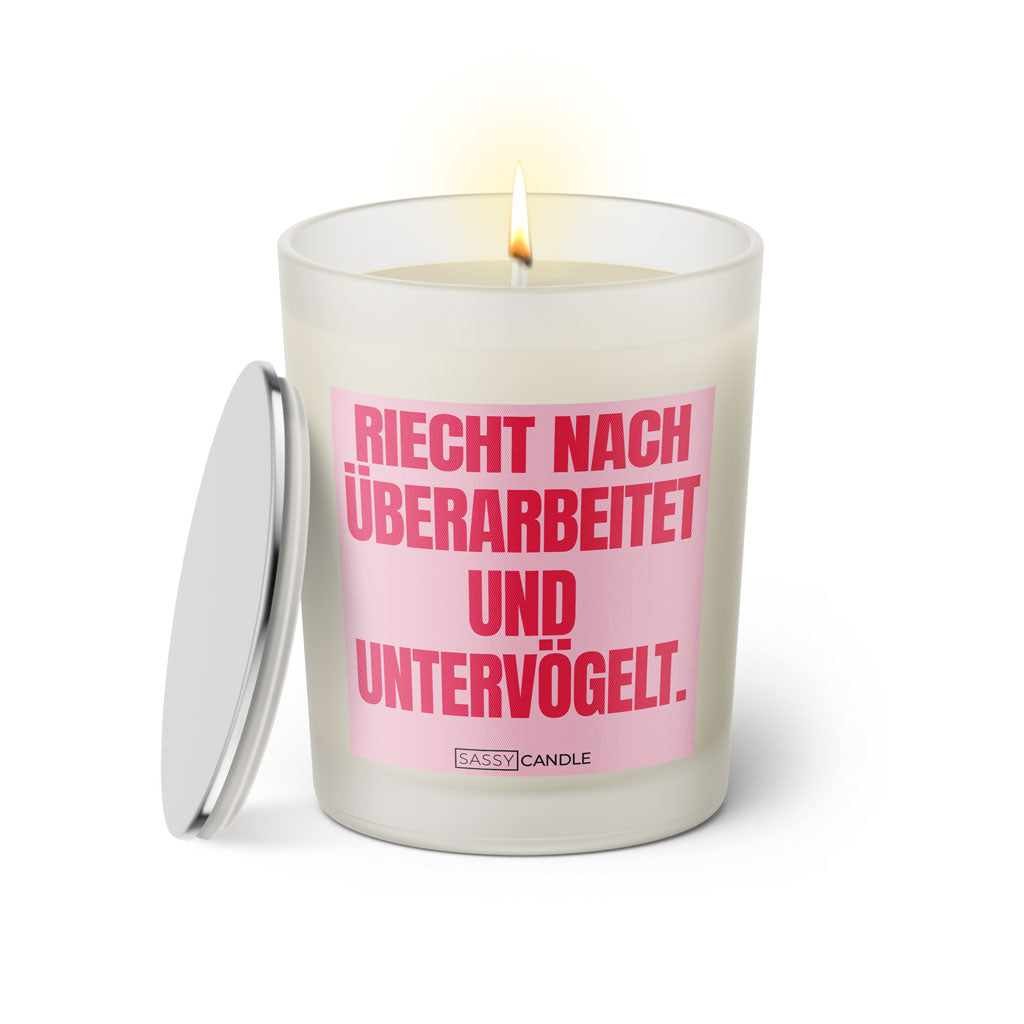 Duftkerze mit witzigem Spruch: Riecht nach untervögelt und überarbeitet. Farbe rosa und pink Schrift. Kerzenglas mit silbernem Deckel von SassyCandle.