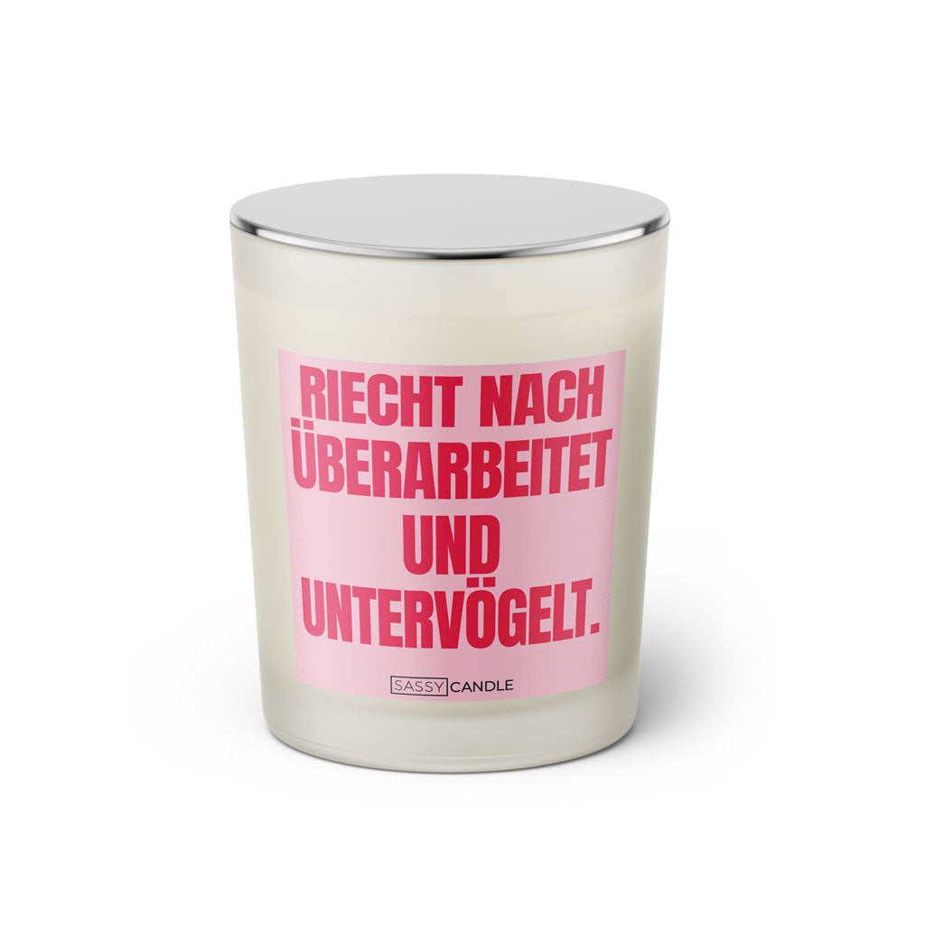 Duftkerze mit witzigem Spruch: Riecht nach untervögelt und überarbeitet. Farbe rosa und pink Schrift. Kerzenglas mit silbernem Deckel von SassyCandle.