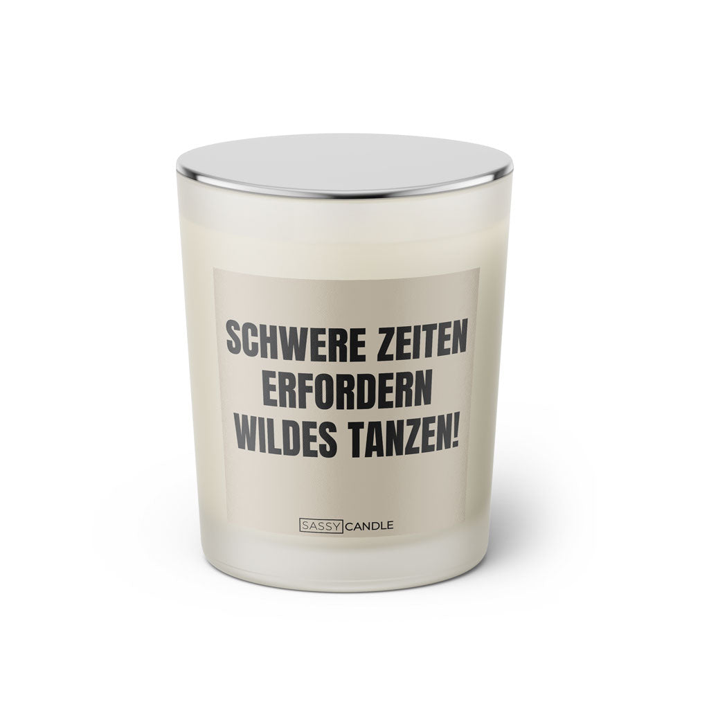 Duftkerze mit witzigem Spruch: Schwere Zeiten erfordern wildes tanzen. Farbe beige und schwarze Schrift. Kerzenglas mit silbernem Deckel von SassyCandle.