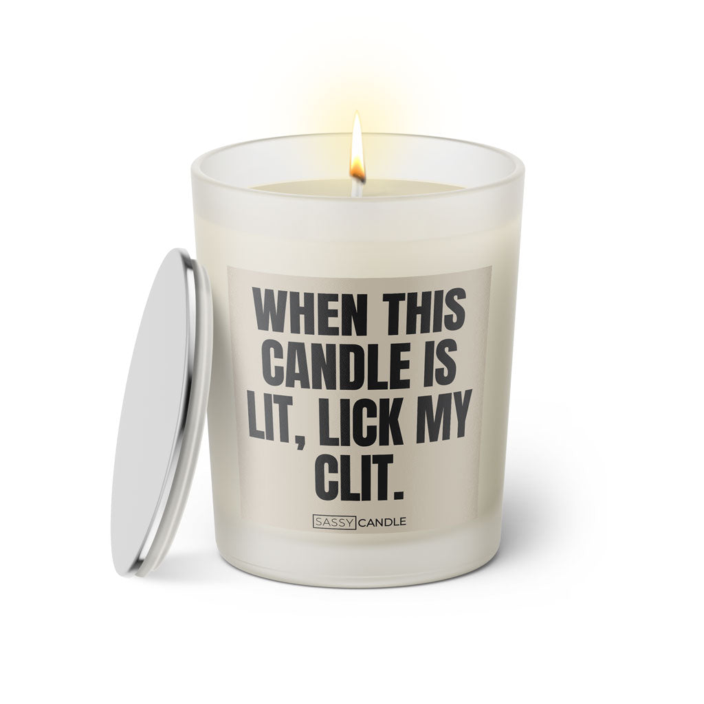 Duftkerze mit witzigem Spruch: When this candle is lit, lick my clit. Farbe beige und schwarze Schrift. Kerzenglas mit silbernem Deckel von SassyCandle.