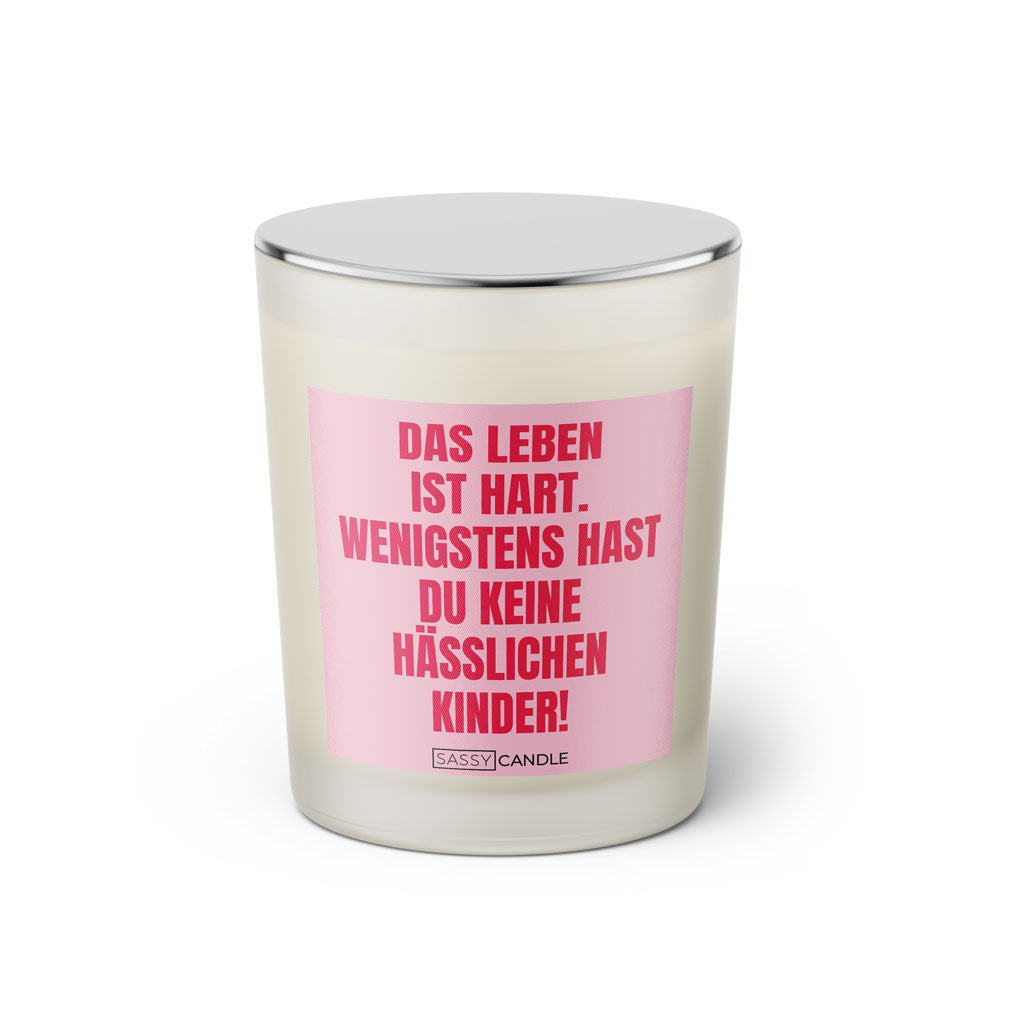 Duftkerze mit witzigem Spruch: Das Leben ist hart. Wenigstens hast du keine hässlichen Kinder. Farbe rosa und pinke Schrift. Kerzenglas mit silbernem geschlossenem Deckel von SassyCandle.