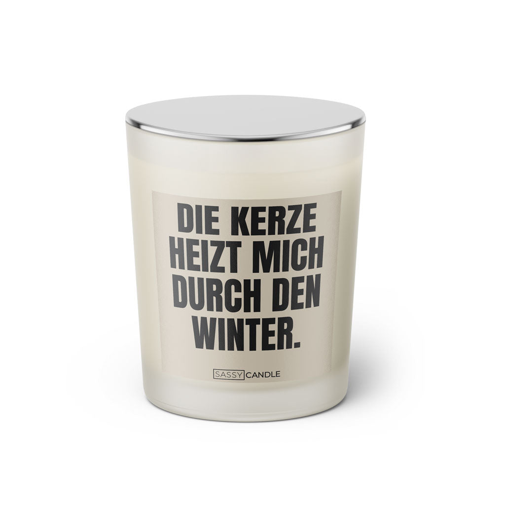Duftkerze mit witzigem Spruch: Die Kerze heizt mich durch den Winter. Farbe beige und schwarze Schrift. Kerzenglas mit silbernem geschlossenem Deckel von SassyCandle.