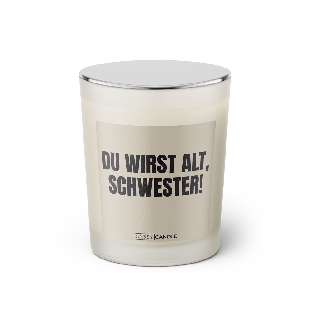 Duftkerze mit witzigem Spruch: Du wirst alt Schwester. Farbe beige und schwarze Schrift. Kerzenglas mit silbernem geschlossenem Deckel von SassyCandle.