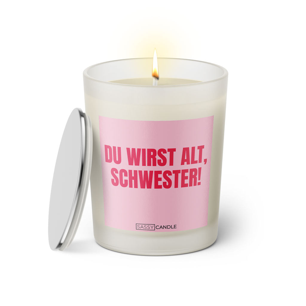 Duftkerze mit witzigem Spruch: Du wirst alt Schwester. Farbe rosa und pinke Schrift. Kerzenglas mit silbernem Deckel von SassyCandle.