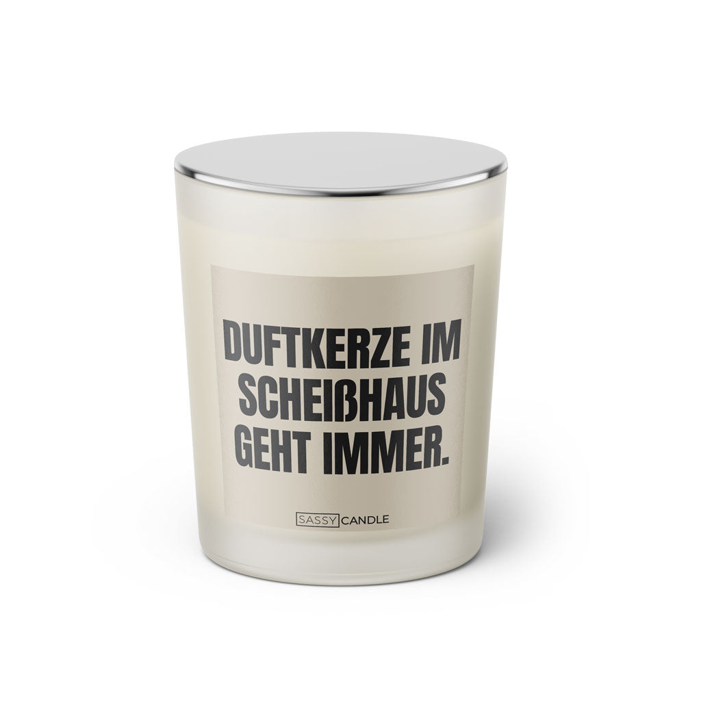 Duftkerze mit witzigem Spruch: Duftkerze im Scheisshaus geht immer. Farbe beige und schwarze Schrift. Kerzenglas mit silbernem Deckel von SassyCandle.