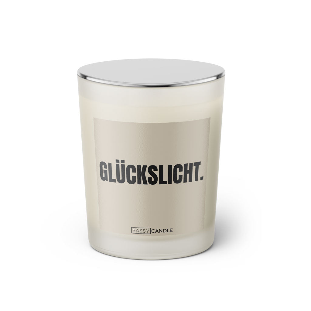 Duftkerze mit witzigen Spruch: Glückslicht. Kerzenglas mit silbernen Deckel. Farbe beige und schwarz von Sassy Candle.