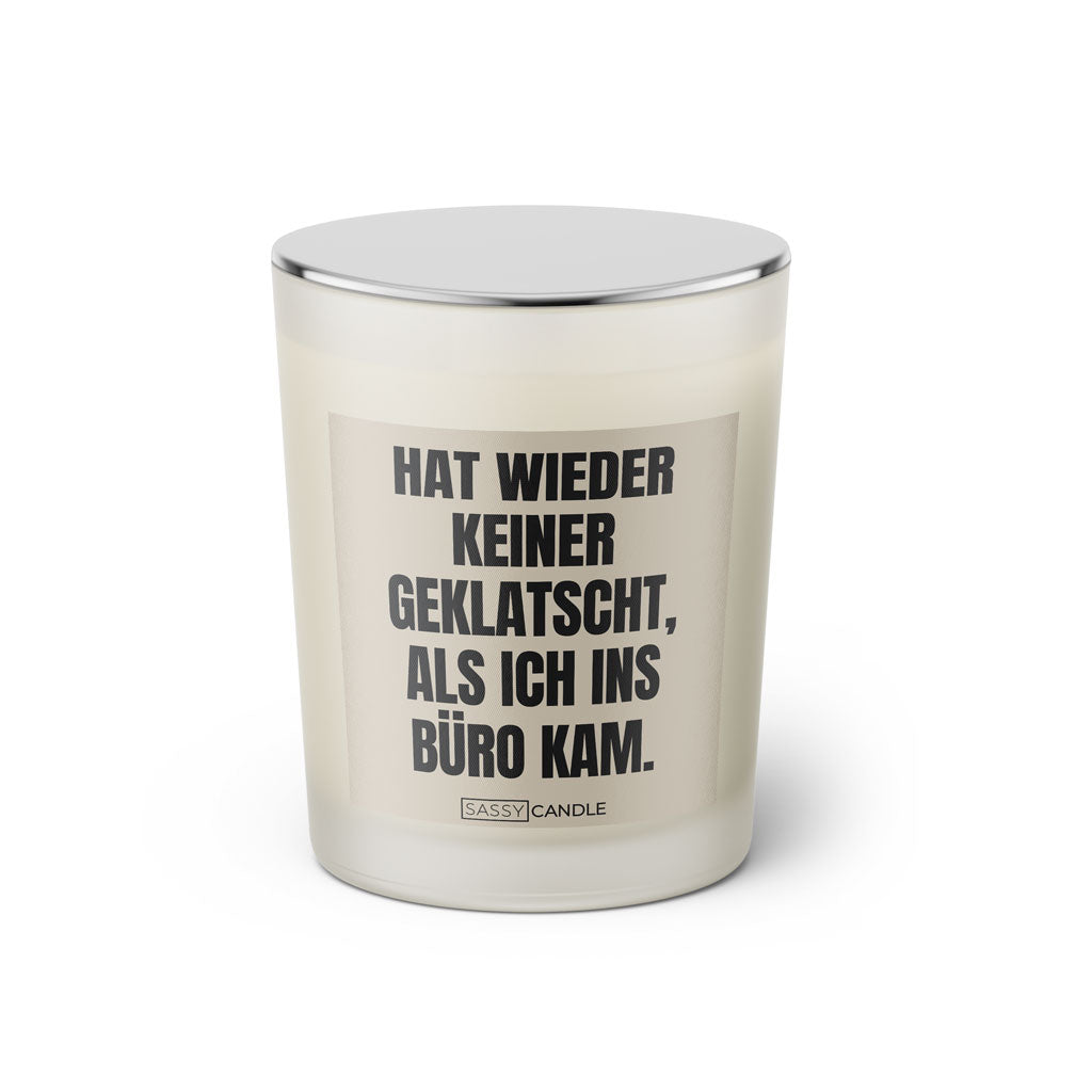 Duftkerze mit witzigem Spruch: Hat wieder keiner geklatscht, als ich ins Büro kam. Farbe schwarz und beige mit silbernem Deckel von Sassy Candle.