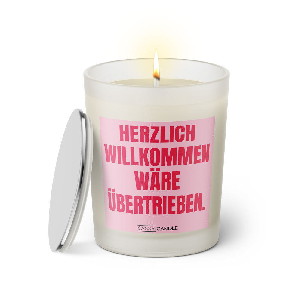 Duftkerze mit witzigem Spruch: Herzlich Willkommen wäre übertrieben. Farbe rosa und pinke Schrift. Kerzenglas mit silbernem Deckel von SassyCandle.
