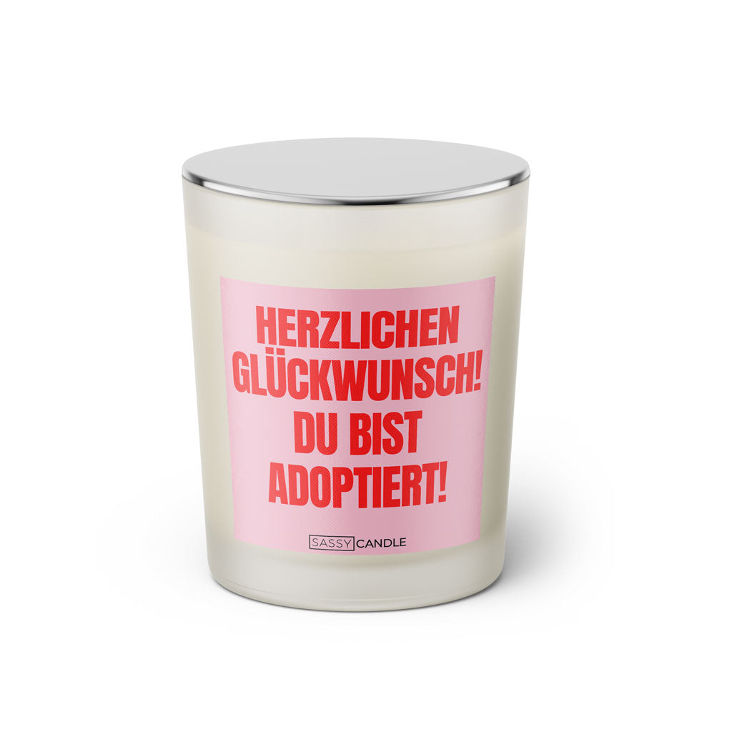 Duftkerze mit witzigen Spruch: Herzlichen Glückwunsch! Du bist adoptiert! Farbe rosa und pink von Sassy Candle.
