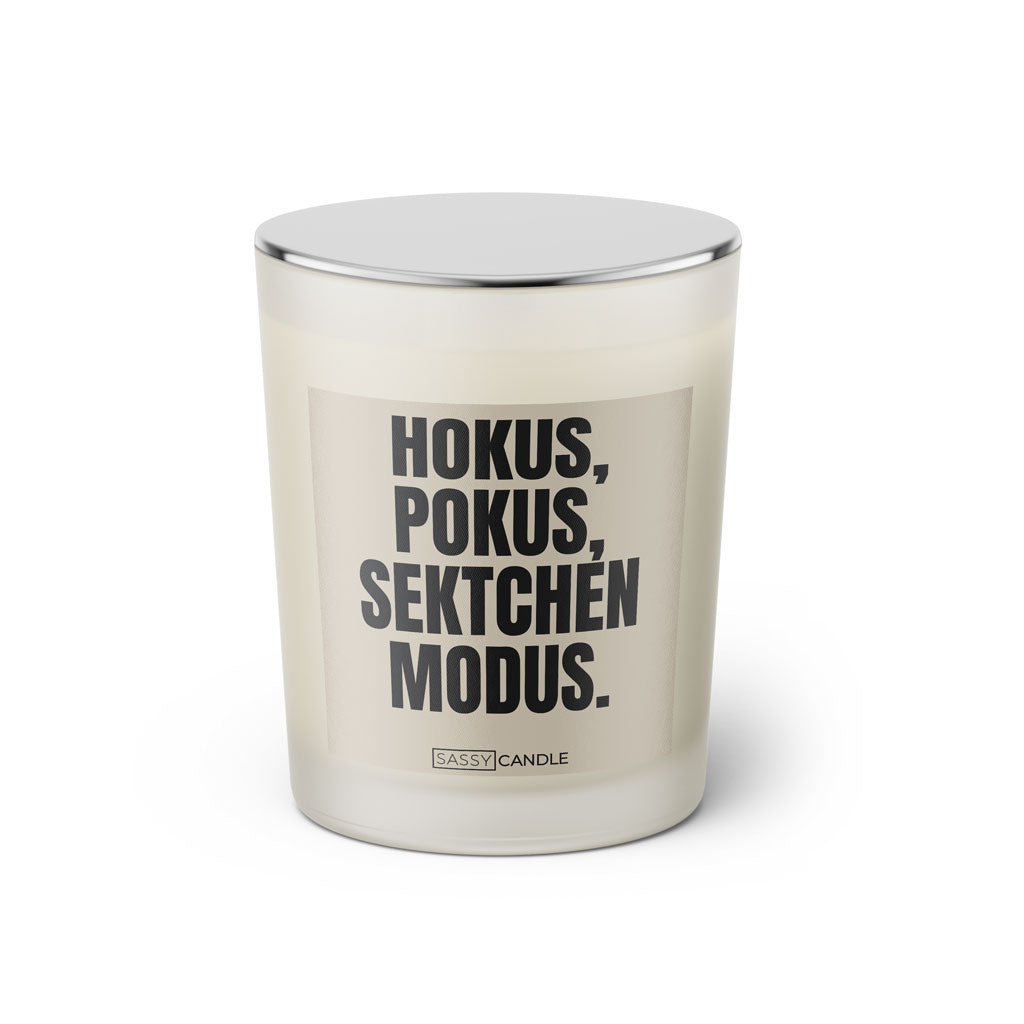 Duftkerze mit witzigem Spruch: Hokus Pokus Sektchen Modus. Farbe beige und schwarze Schrift. Kerzenglas mit silbernem geschlossenem Deckel von SassyCandle.