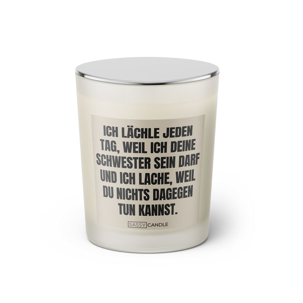 Duftkerze mit witzigen Spruch: Ich lächle jeden Tag, weil ich deine Schwester sein darf und ich lache, weil du nichts dagegen tun kannst. Kerzenglas mit silbernen Deckel. Farbe beige und schwarz von Sassy Candle.