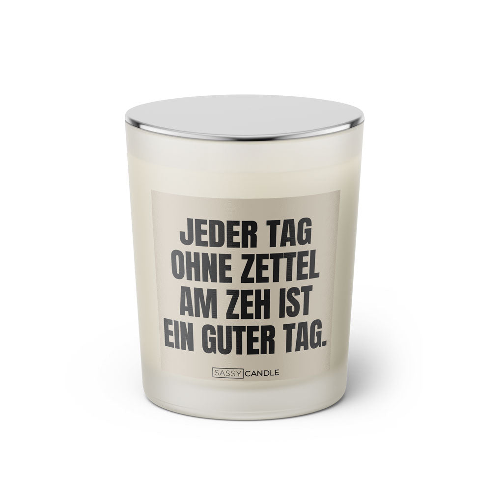 Duftkerze mit witzigen Spruch: Jeder Tag ohne Zettel am Zeh ist ein guter Tag. Kerzenglas mit silbernen Deckel von Sassy Candle. Farbe beige und schwarz.