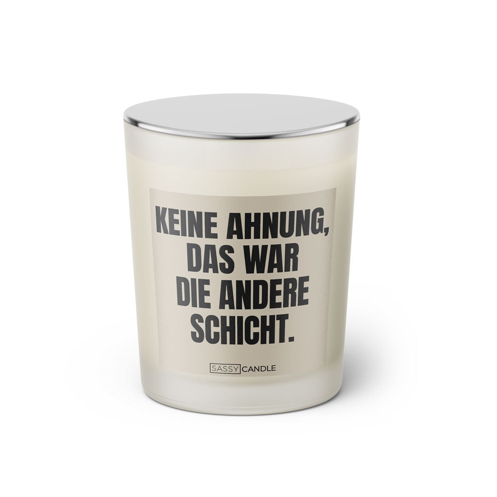 Duftkerze mit witzigem Spruch: Keine Ahnung, das war die andere Schicht. Farbe beige und schwarz mit silbernem Deckel von Sassy Candle.