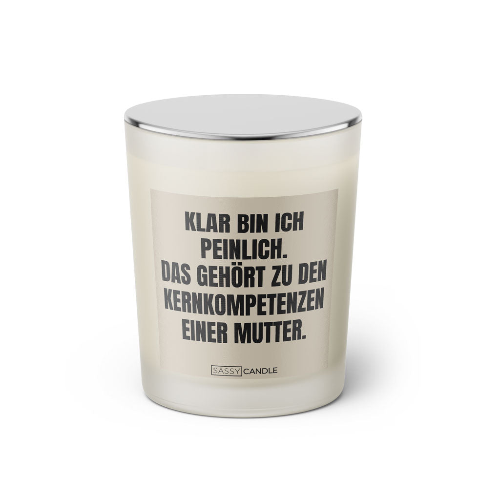 Duftkerze mit witzigem Spruch: Klar bin ich peinlich. Das gehört zu den Kernkompetenzen einer Mutter. Farbe beige und schwarze Schrift. Kerzenglas mit silbernem geschlossenem Deckel von SassyCandle.