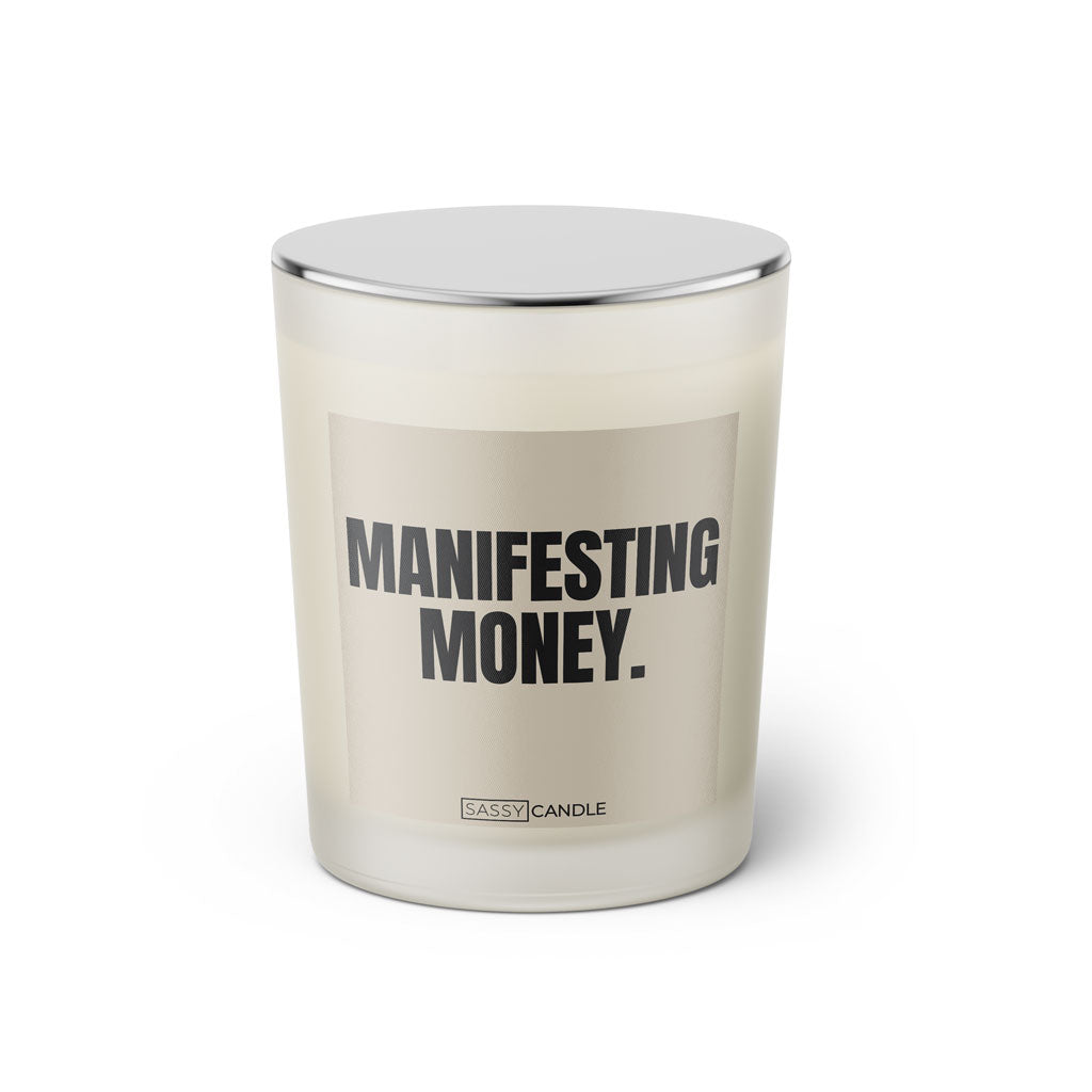 Duftkerze mit witzigem Spruch: Manifestant Money. Farbe beige und schwarze Schrift. Kerzenglas mit silbernem geschlossenem Deckel von SassyCandle.