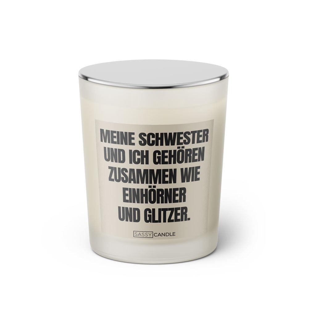 Duftkerze mit witzigem Spruch: Meine Schwester und ich gehören zusammen wie Einhörner und Glitzer! Farbe beige und schwarze Schrift. Kerzenglas mit silbernem geschlossenem Deckel von SassyCandle.