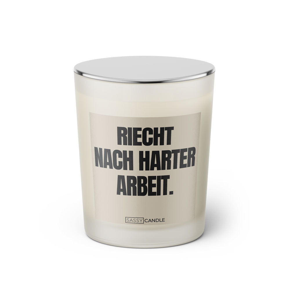 Duftkerze mit witzigem Spruch: Riecht nach harter Arbeit. Farbe beige und schwarze Schrift. Kerzenglas mit silbernem geschlossenem Deckel von SassyCandle.