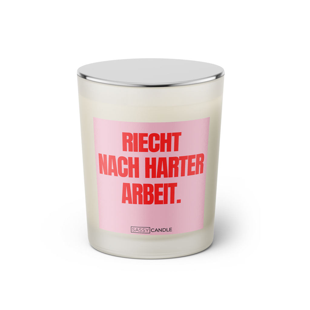 Duftkerze mit witzigem Spruch: Riecht nach harter Arbeit. Farbe rosa und pinke Schrift. Kerzenglas mit silbernem geschlossenem Deckel von SassyCandle.