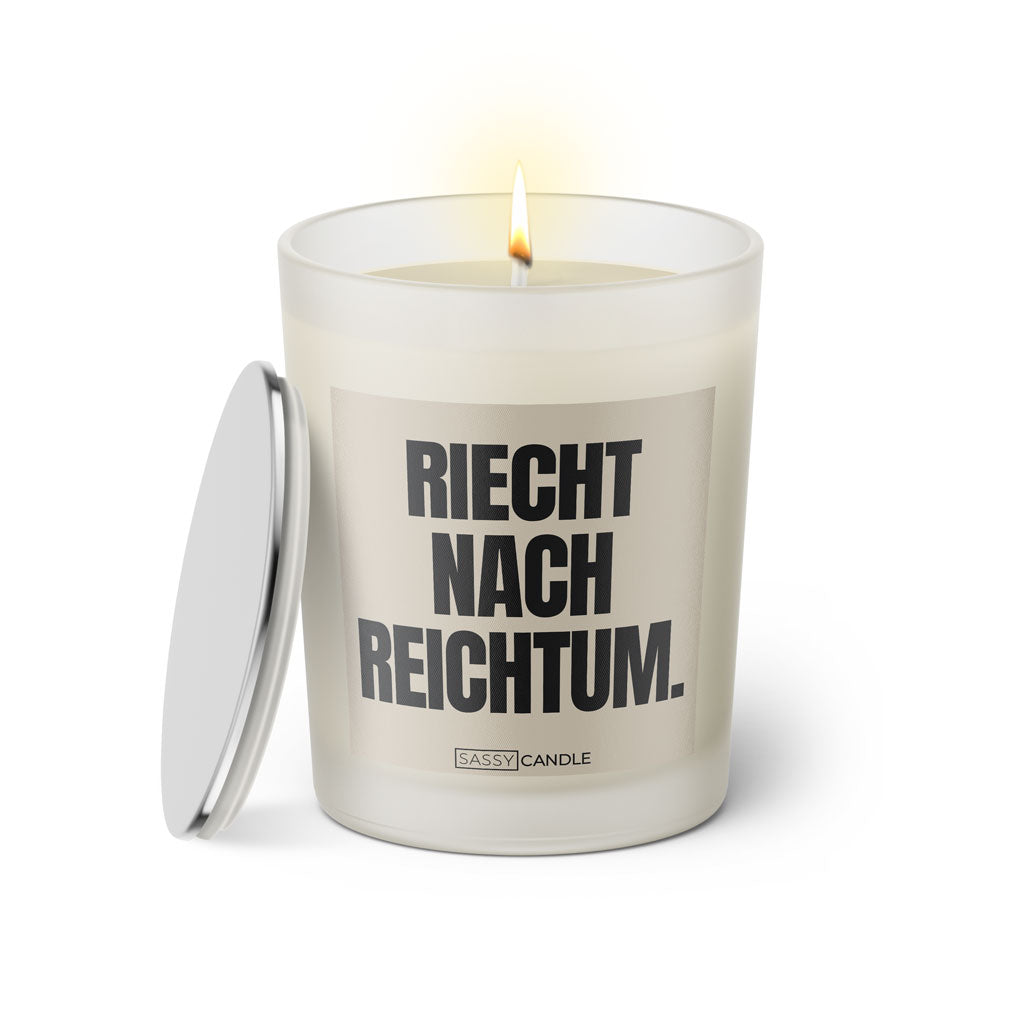 Duftkerze mit Spruch: Riecht nach Reichtum. Farbe beige und schwarz von Sassy Candle.
