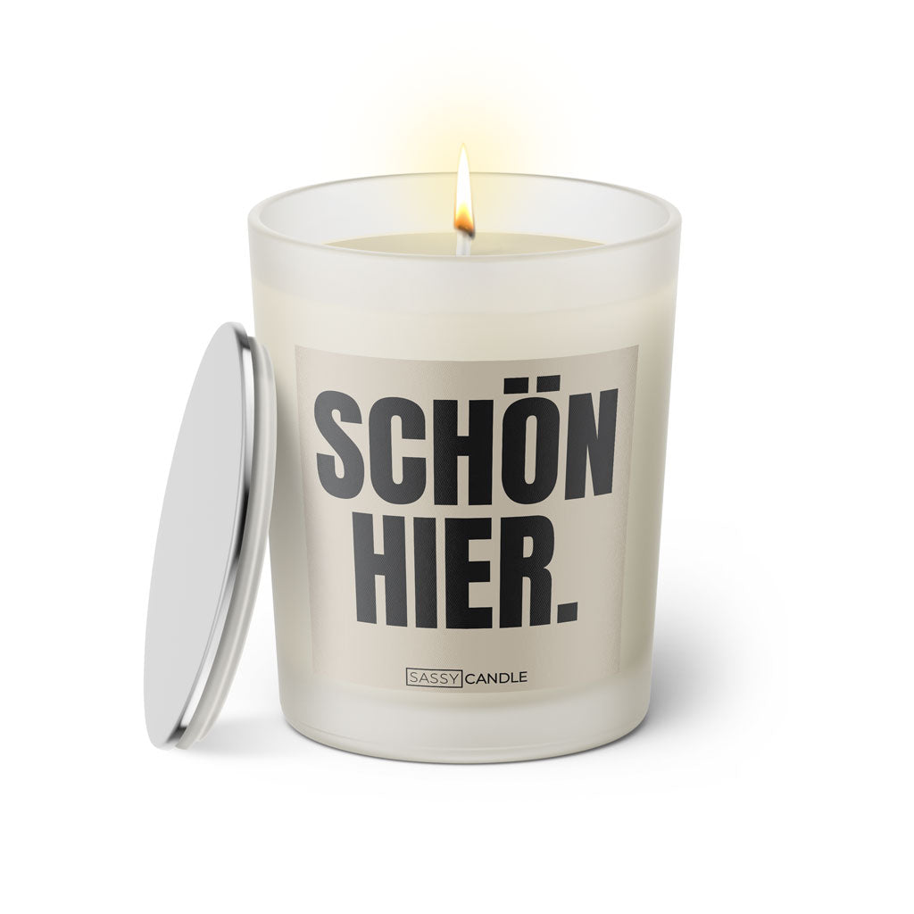 Duftkerze mit witzigem Spruch: Schön hier. Farbe beige und schwarze Schrift. Kerzenglas mit silbernem Deckel von SassyCandle.