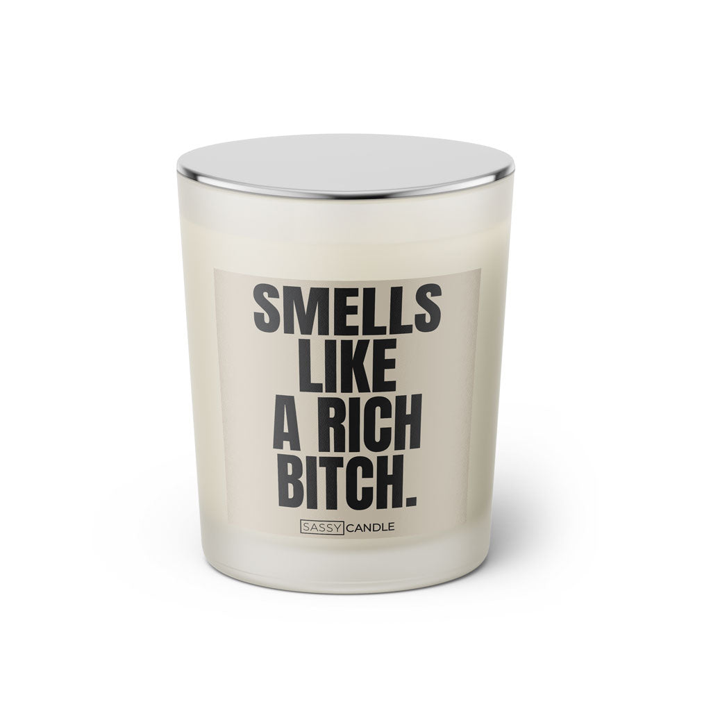 Duftkerze mit witzigem Spruch: Smells like a rich bitch. Farbe beige und schwarze Schrift. Kerzenglas mit silbernem geschlossenem Deckel von SassyCandle.