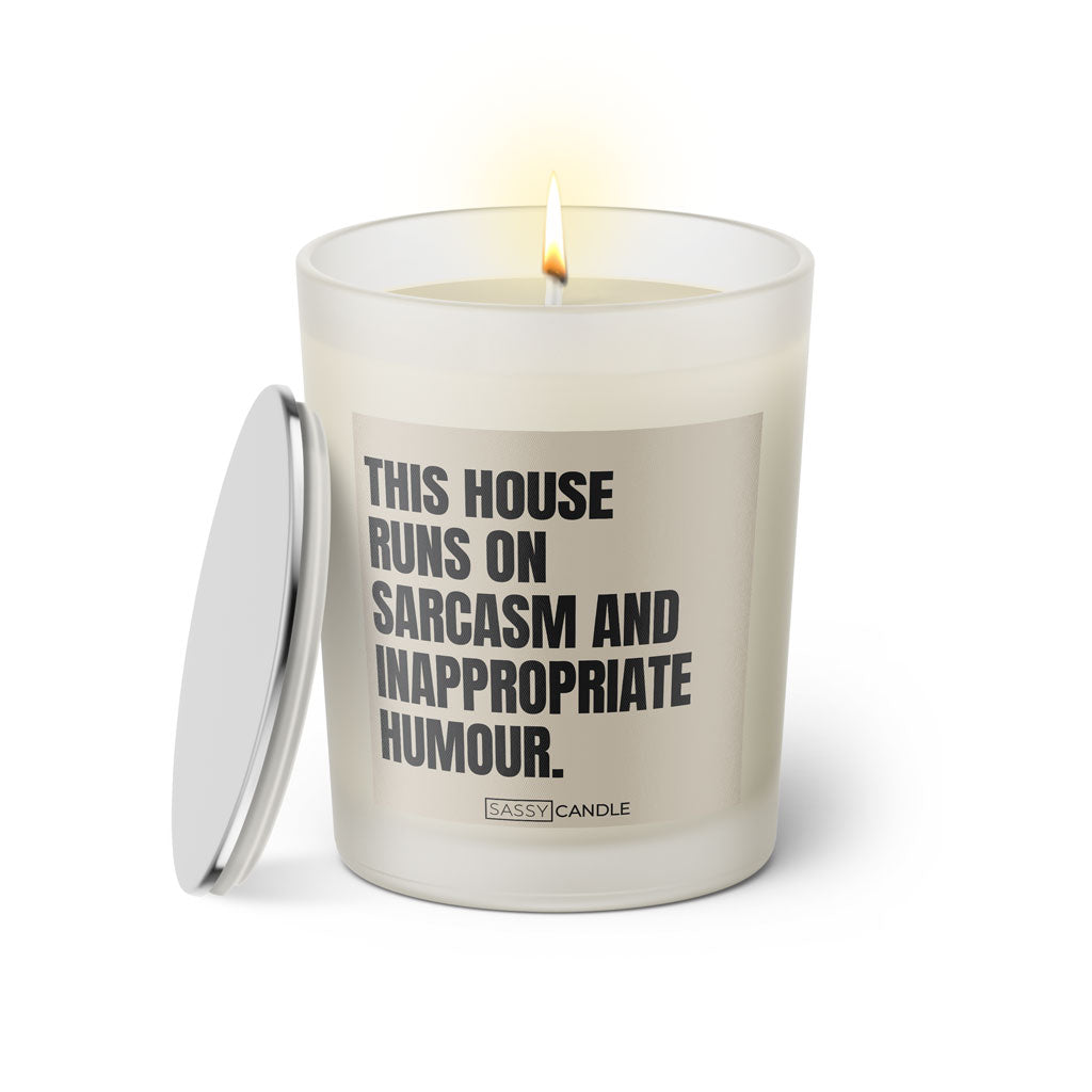 Duftkerze mit witzigen Spruch: This house runs on sarcasm and inappropriate humour. Farbe beige und schwarz. Kerze von Sassy Candle.