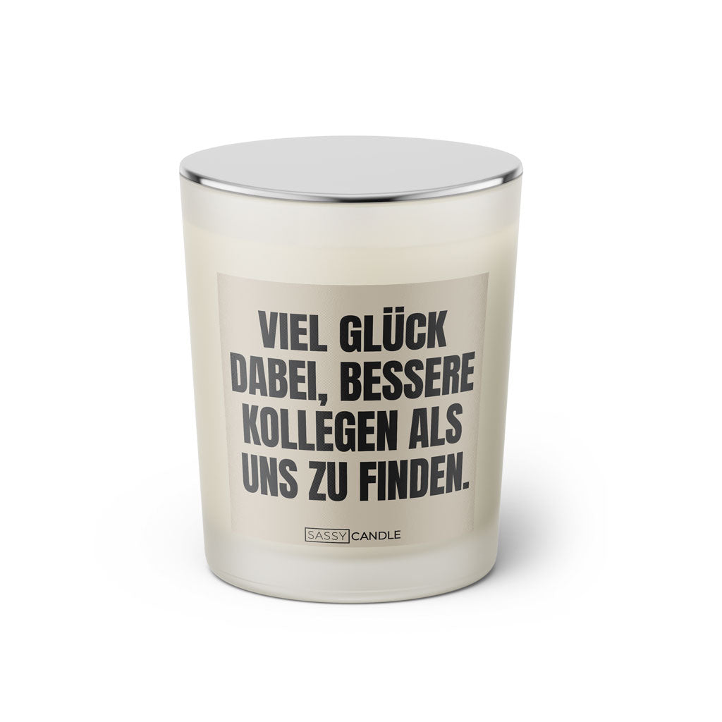Duftkerze mit witzigem Spruch: Viel Glück dabei, bessere Kollegen als uns zu finden. Farbe beige und schwarze Schrift. Kerzenglas mit silbernem Deckel von SassyCandle.