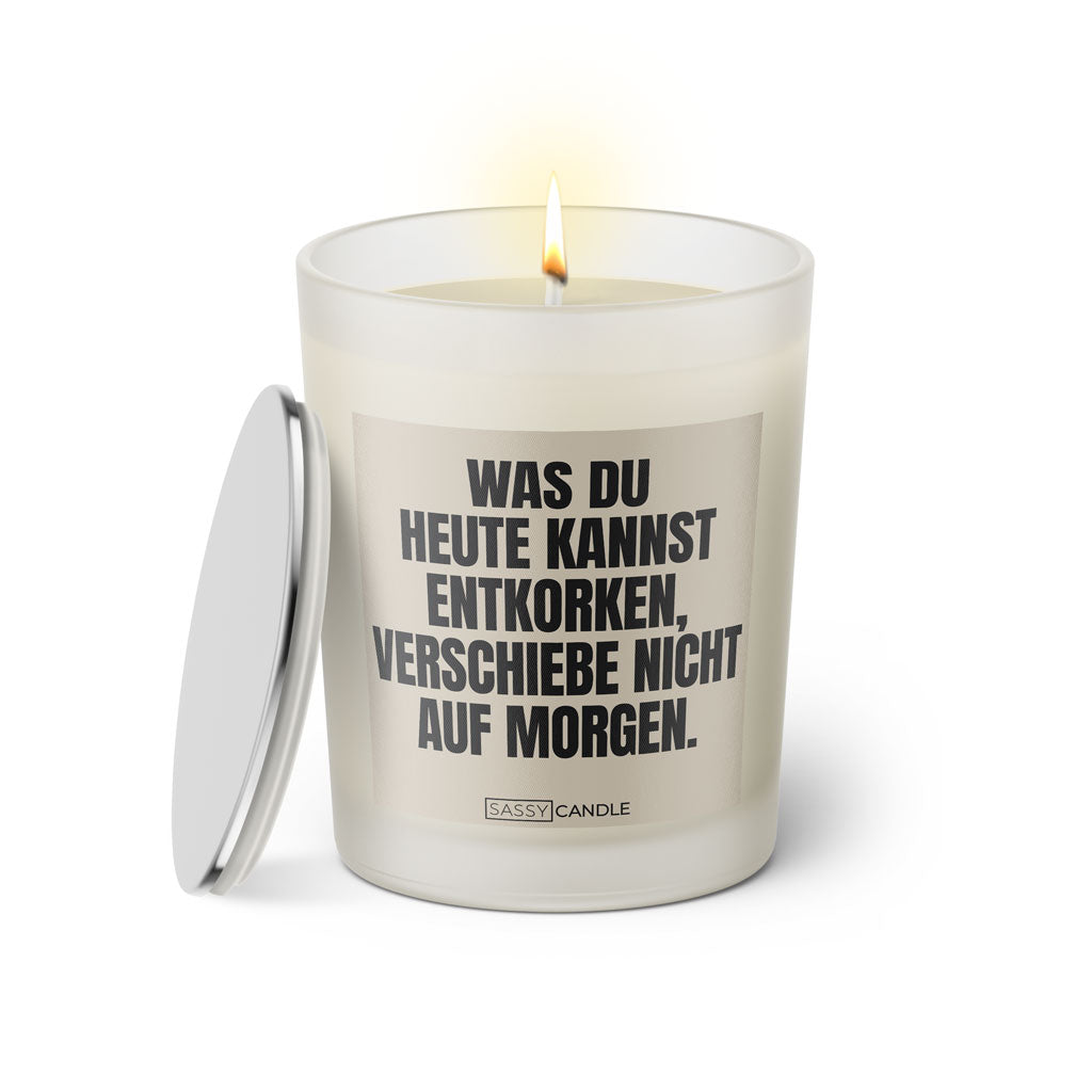 Duftkerze mit witzigem Spruch: Was du heute kannst entkorken, verschiebe nicht auf morgen. Farbe beige und schwarze Schrift. Kerzenglas mit silbernem Deckel von SassyCandle.