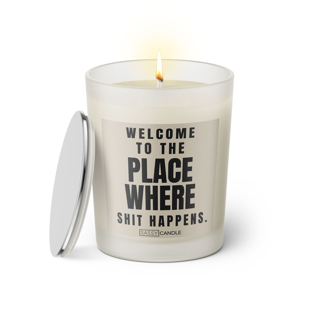 Duftkerze mit witzigen Spruch: Welcome to the place where shit happens. Kerzenglas mit silbernen Deckel von Sassy Candle. Farbe beige und schwarz.