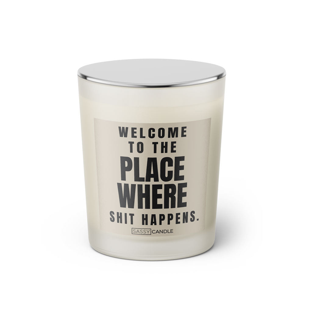 Duftkerze mit witzigen Spruch: Welcome to the place where shit happens. Kerzenglas mit silbernen Deckel von Sassy Candle. Farbe beige und schwarz.