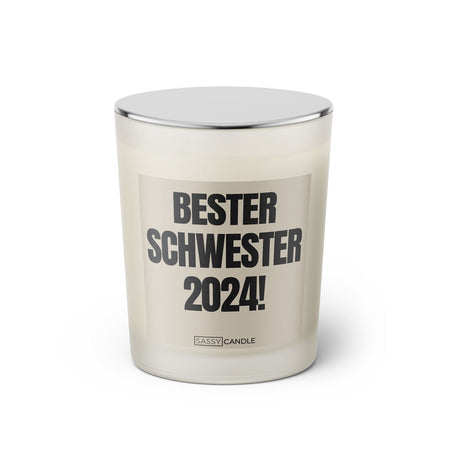 Duftkerze mit witzigem Spruch: Bester Schwester 2024. Farbe beige und schwarze Schrift. Kerzenglas mit silbernem geschlossenem Deckel von SassyCandle.