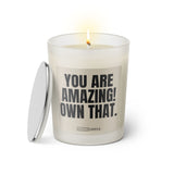 Duftkerze mit witzigem Spruch: You are amazing! Own that. Farbe beige und schwarze Schrift. Kerzenglas mit silbernem Deckel von SassyCandle.