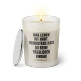 Duftkerze mit witzigem Spruch: Das Leben ist hart. Wenigstens hast du keine hässlichen Kinder. Farbe beige und schwarze Schrift. Kerzenglas mit silbernem Deckel von SassyCandle