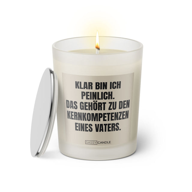 Duftkerze mit witzigem Spruch: Klar bin ich peinlich. Das gehört zu den Kernkompetenzen eines Vaters. Farbe beige und schwarze Schrift. Kerzenglas mit silbernem Deckel von SassyCandle.