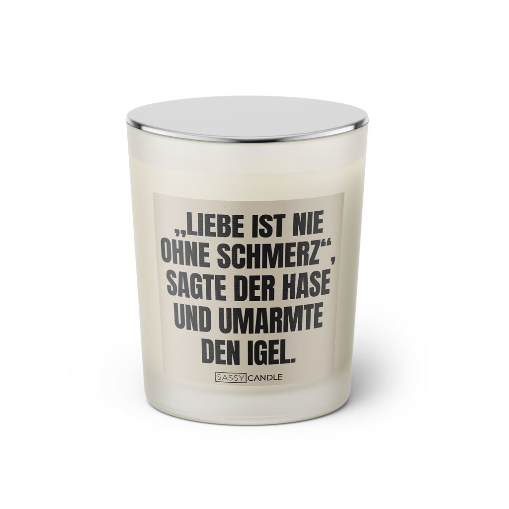 Duftkerze mit Spruch: Liebe ist nie ohne Schmerz, sagte der Hase und umarmte den Igel. Farbe beige und schwarz mit silbernem Deckel von Sassy Candle.