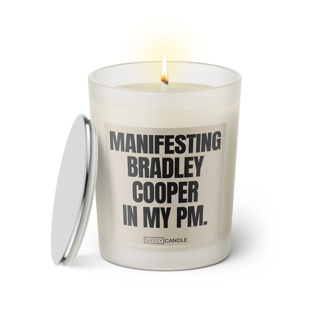 Duftkerze mit witzigen Spruch: Manifesting Bradley Cooper in my PM. Farbe beige und schwarz von Sassy Candle.