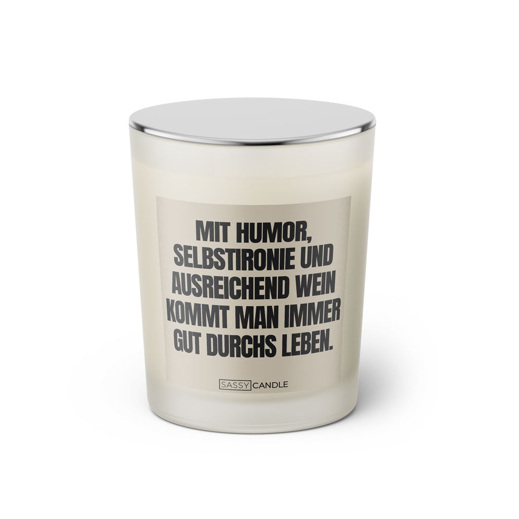 Duftkerze mit witzigem Spruch: Mit Humor, Selbstironie und ausreichend Wein kommt man immer gut durchs Leben. Farbe beige und schwarze Schrift. Kerzenglas mit silbernem geschlossenem Deckel von SassyCandle.