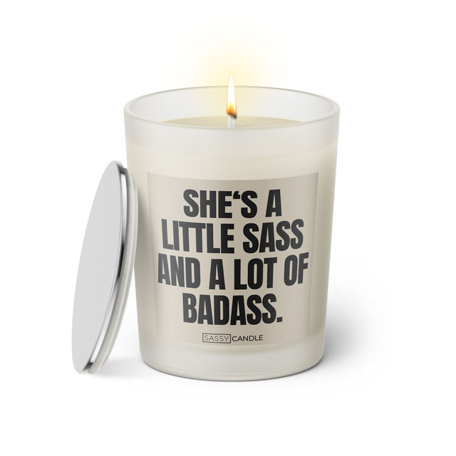 Duftkerze mit witzigen Spruch: She's a little sass and a lot of badass. Farbe beige und schwarz mit silbernen Deckel von Sassy Candle.
